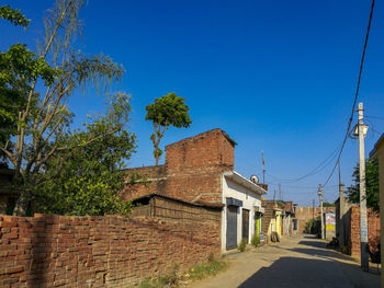 Road amidst trees and buildings against blue sky