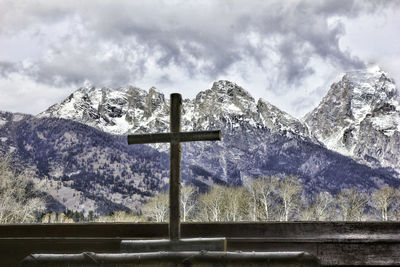 Cross on snowcapped mountains against sky