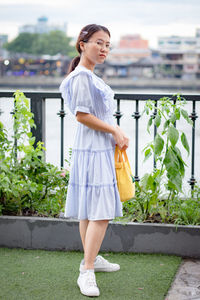 Portrait of woman standing by railing