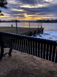 Wooden fence on beach against sky during sunset