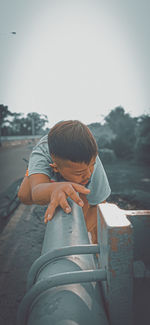 Rear view of boy holding umbrella against sky