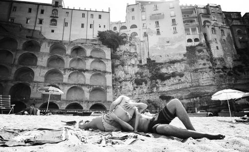 People relaxing against buildings in city