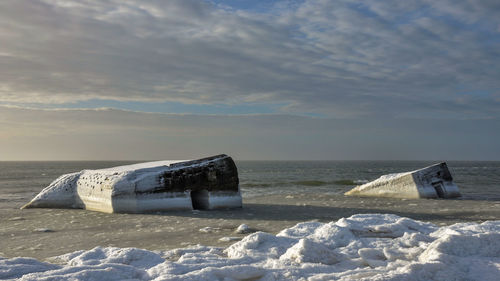 Lifeguard hut on beach against sky during winter