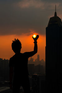 Silhouette man standing against orange sky