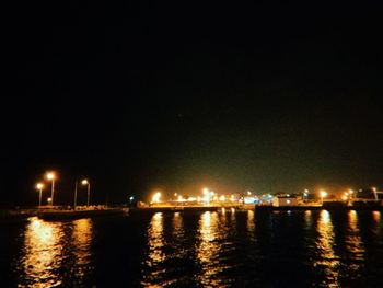 River by illuminated buildings against clear sky at night