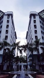 Low angle view of palm trees by swimming pool against sky