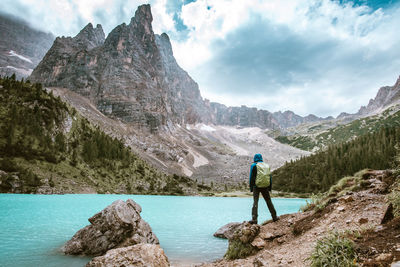 Rear view of man looking at mountains against sky