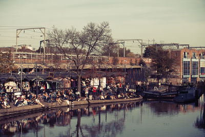 Boats in river by buildings in city against sky