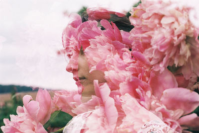 Double exposure image of woman and pink flowers standing outdoors