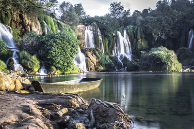 Scenic view of waterfall against trees and rock formation