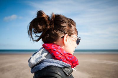 Side view of mid adult woman standing at beach against sky