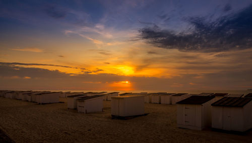 Beach huts against sky during sunset