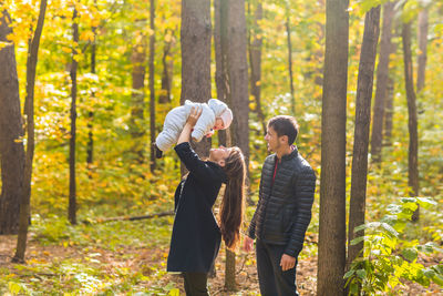 Full length of friends standing by tree in forest