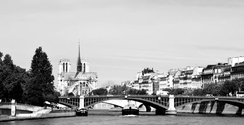 Bridge over river by buildings against sky