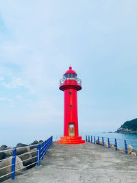 Lighthouse by sea against sky