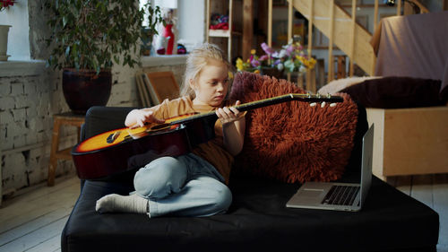 Cute girl playing guitar at home