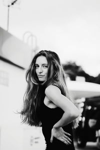 Portrait of young woman standing against white background