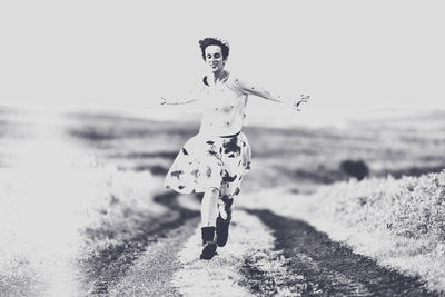 Woman running on dirt road against clear sky