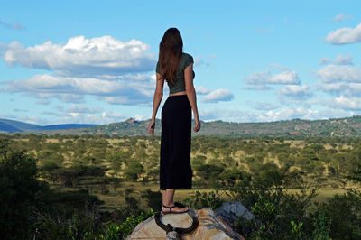 Rear view of woman standing on landscape against sky