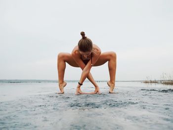 Full length of young woman standing on beach against clear sky