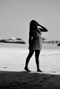 Full length of woman standing on beach against sky