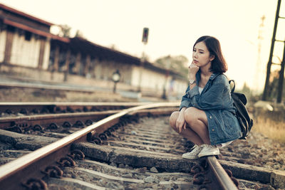 Young woman sitting on railroad track