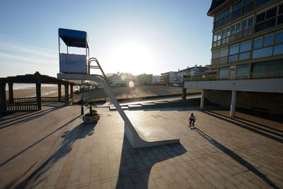 Side view of unrecognizable male skater riding down rescue tower located on seashore in summer