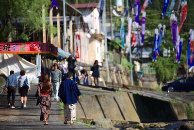 People walking on footpath against koinobori