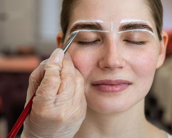 Close-up of young woman applying make-up