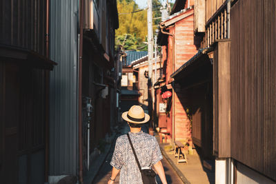 Rear view of man wearing hat walking at alley