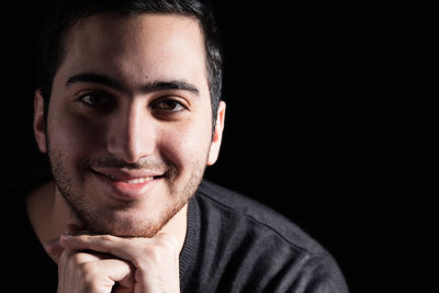 Portrait of smiling young man against black background