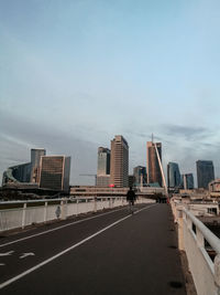 Road by buildings against sky in city