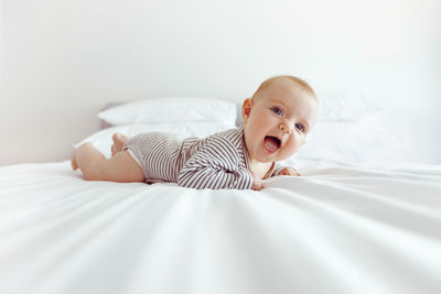 Charming happy baby on white bed