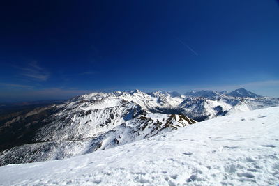 Scenic view of snowcapped mountains against blue sky