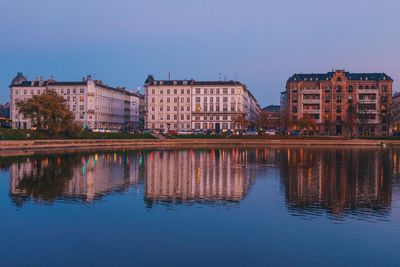 Reflection of buildings in lake against clear sky