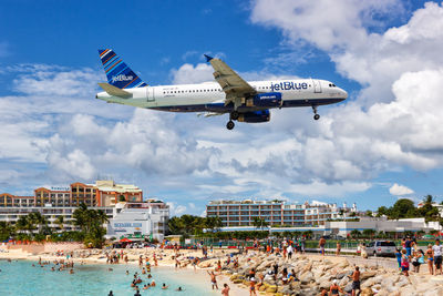 People at airplane against sky