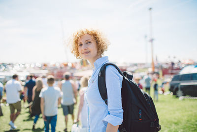 Portrait of smiling woman walking in city against sky