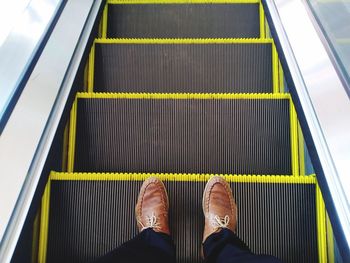 Low section of man standing on escalator