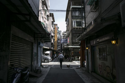 Rear view of people walking on street amidst buildings in city