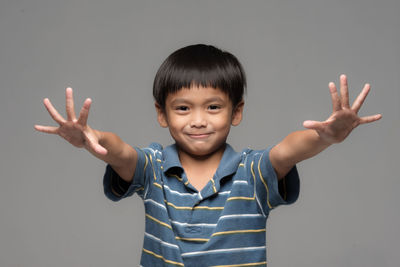 Portrait of boy gesturing against gray background