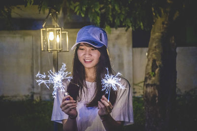 Portrait of a smiling young woman standing at night