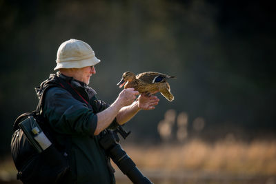 Side view of man holding a duck