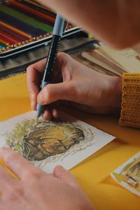 Close-up of woman drawing in paper on table