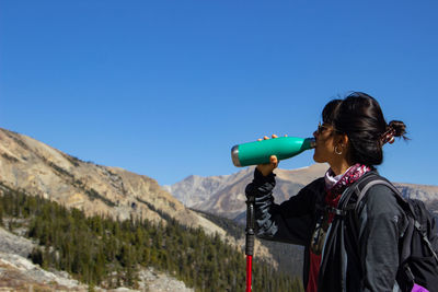 Rear view of woman standing against clear blue sky