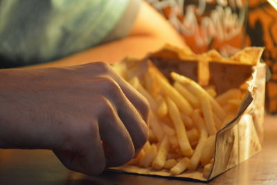 Cropped hands of man eating french fries