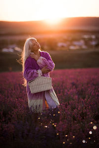 Woman holding basket standing in flower field