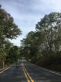 Man riding motorcycle on road against sky