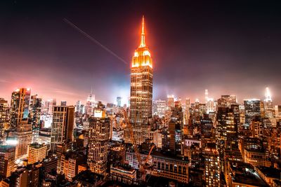 Illuminated cityscape against sky at night