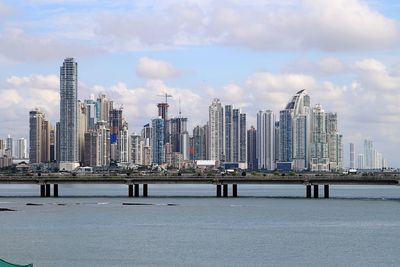 City at waterfront against cloudy sky