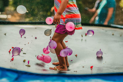 Low section of kid jumping amidst water bombs on trampoline